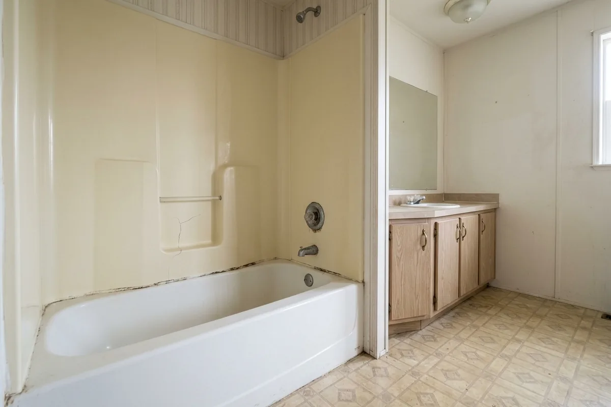 Dated mobile home bathroom with a yellowed fiberglass tub surround before remodeling
